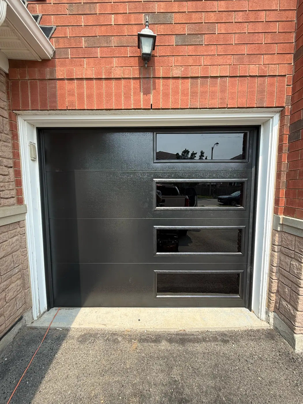 Black flush garage door with glass lites, representing homes in Etobicoke and across Toronto
