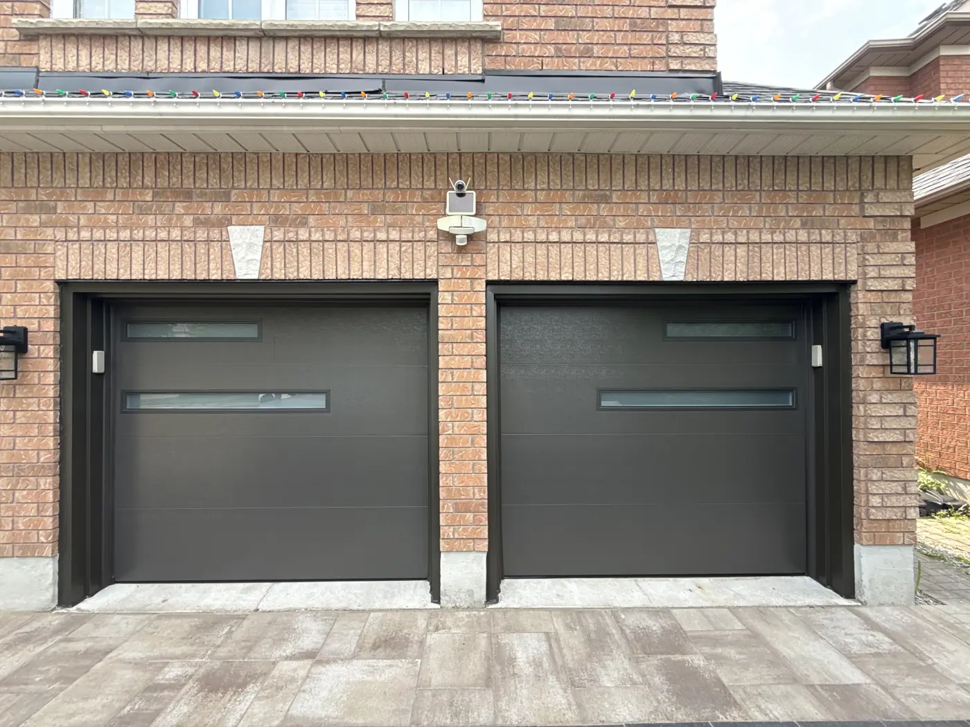 Two black modern garage doors installed on a brick home, similar to new door installs in Brampton